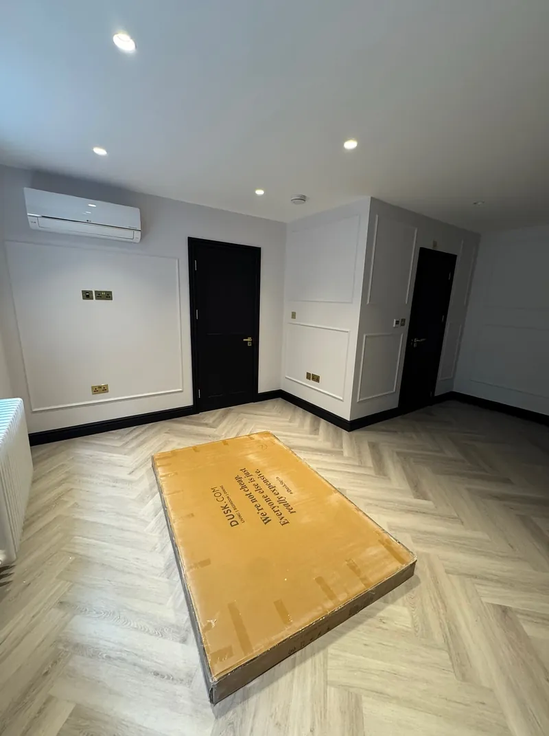 Open-plan living area in a renovated Mayfair flat with herringbone flooring and white walls