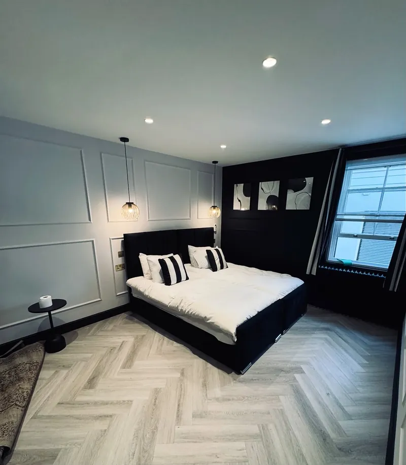 Furnished bedroom in a renovated Mayfair flat with panelled walls and a herringbone floor