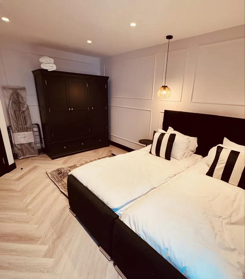 Furnished bedroom in a renovated Mayfair flat with downlights, a pendant light and a herringbone floor