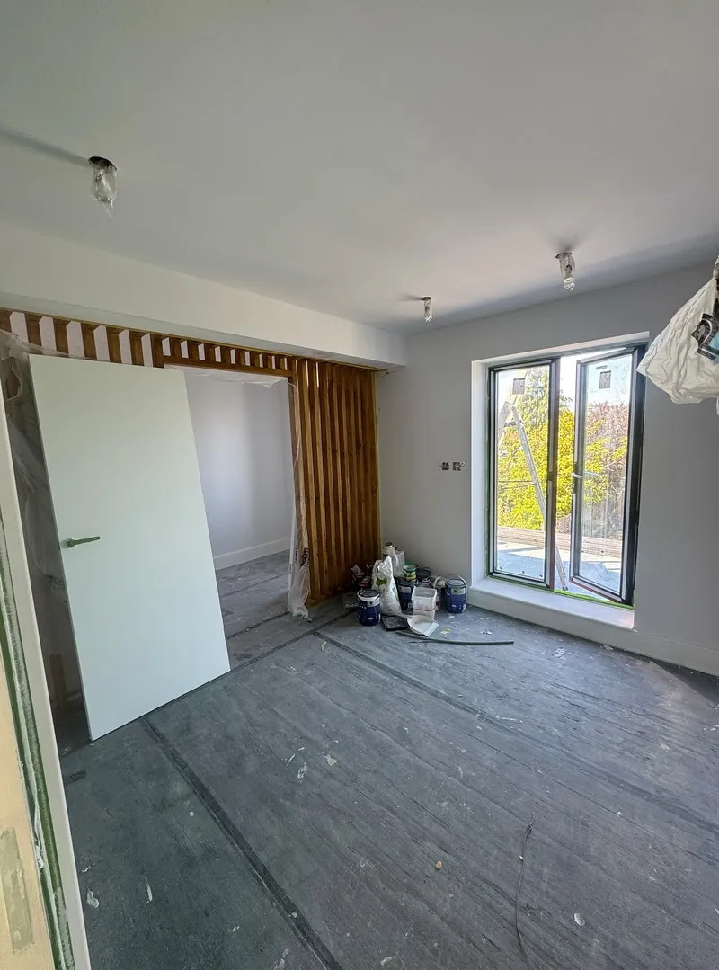 First-floor room in Wembley freshly painted, with the floor protected and doors waiting to be hung