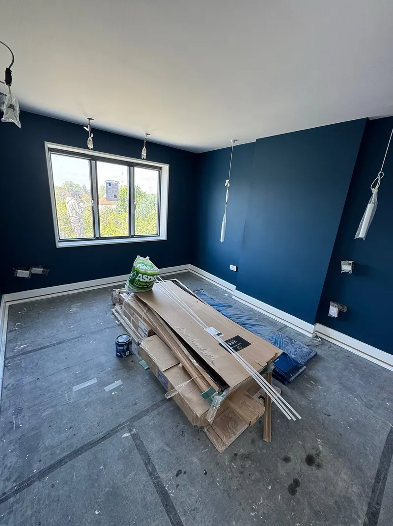 Master bedroom in Wembley painted navy, with timber stacked on the floor ready for the balcony frame